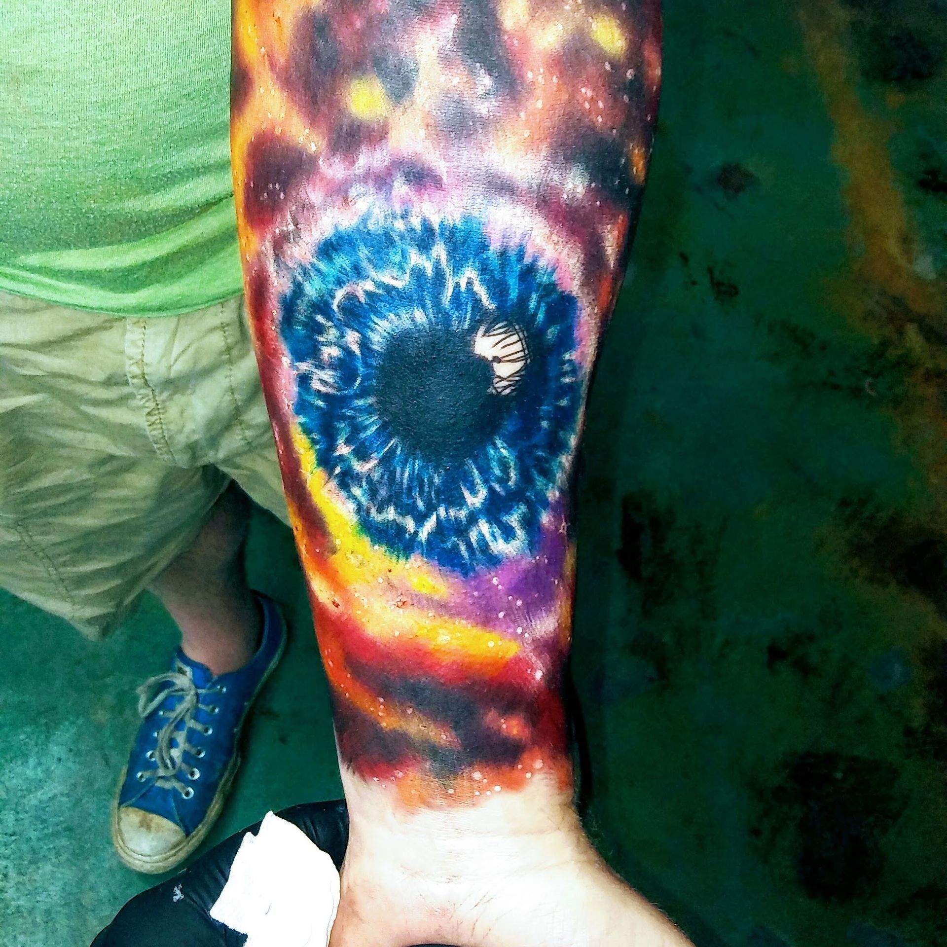 A person has a colorful tattoo of an eye on their arm