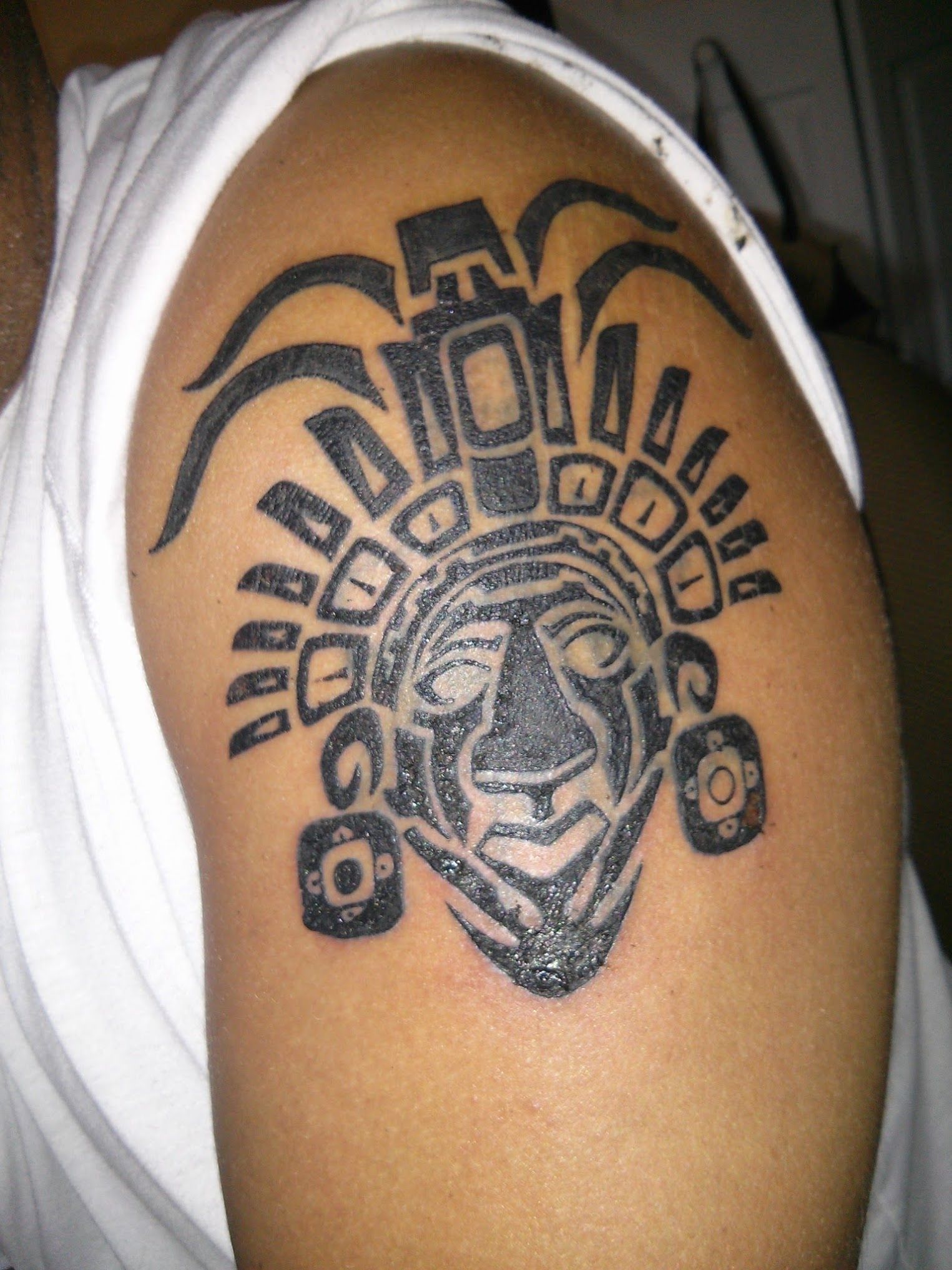 A man has a black and white tattoo on his shoulder