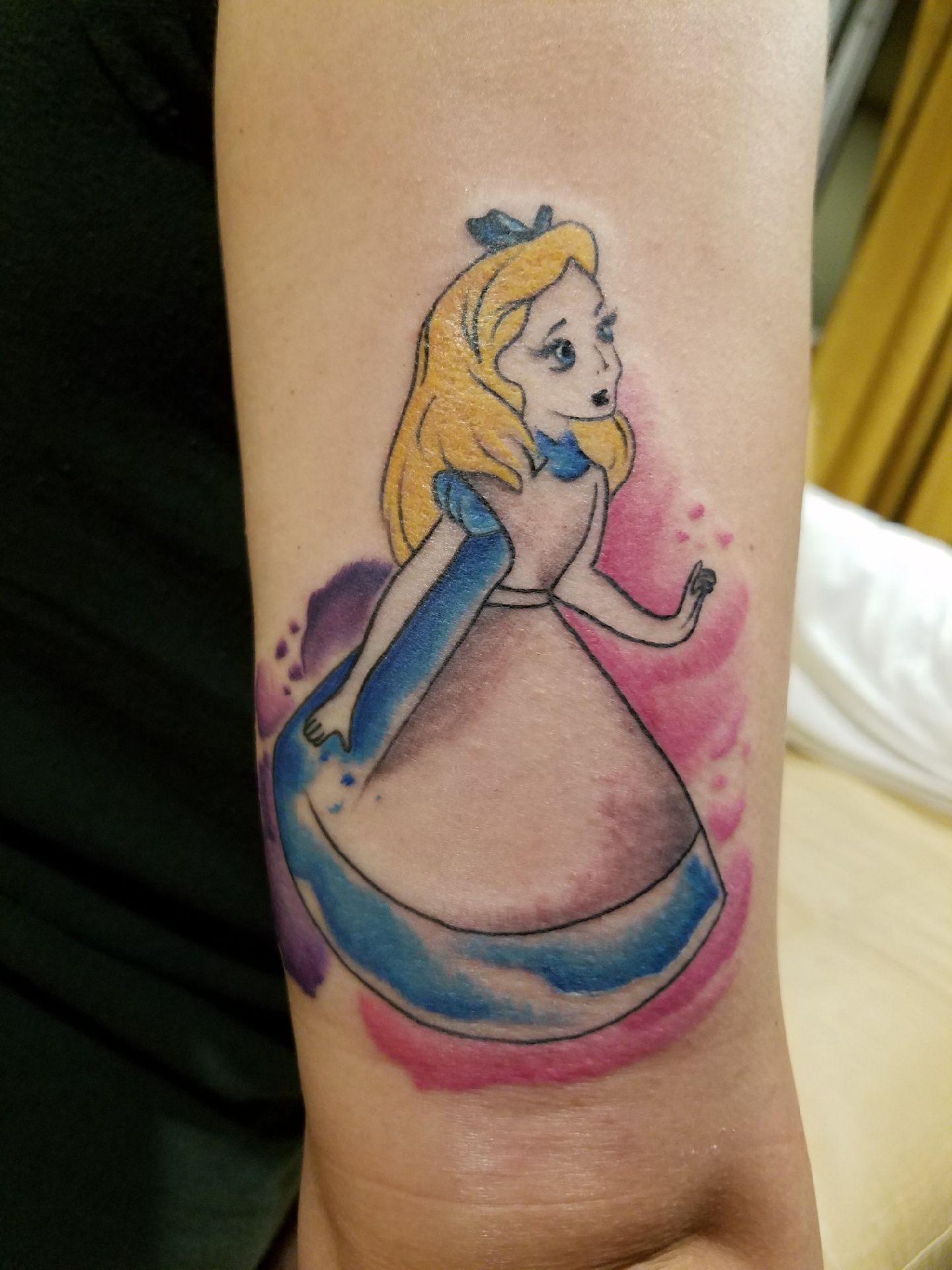 A woman has a tattoo of alice from alice in wonderland