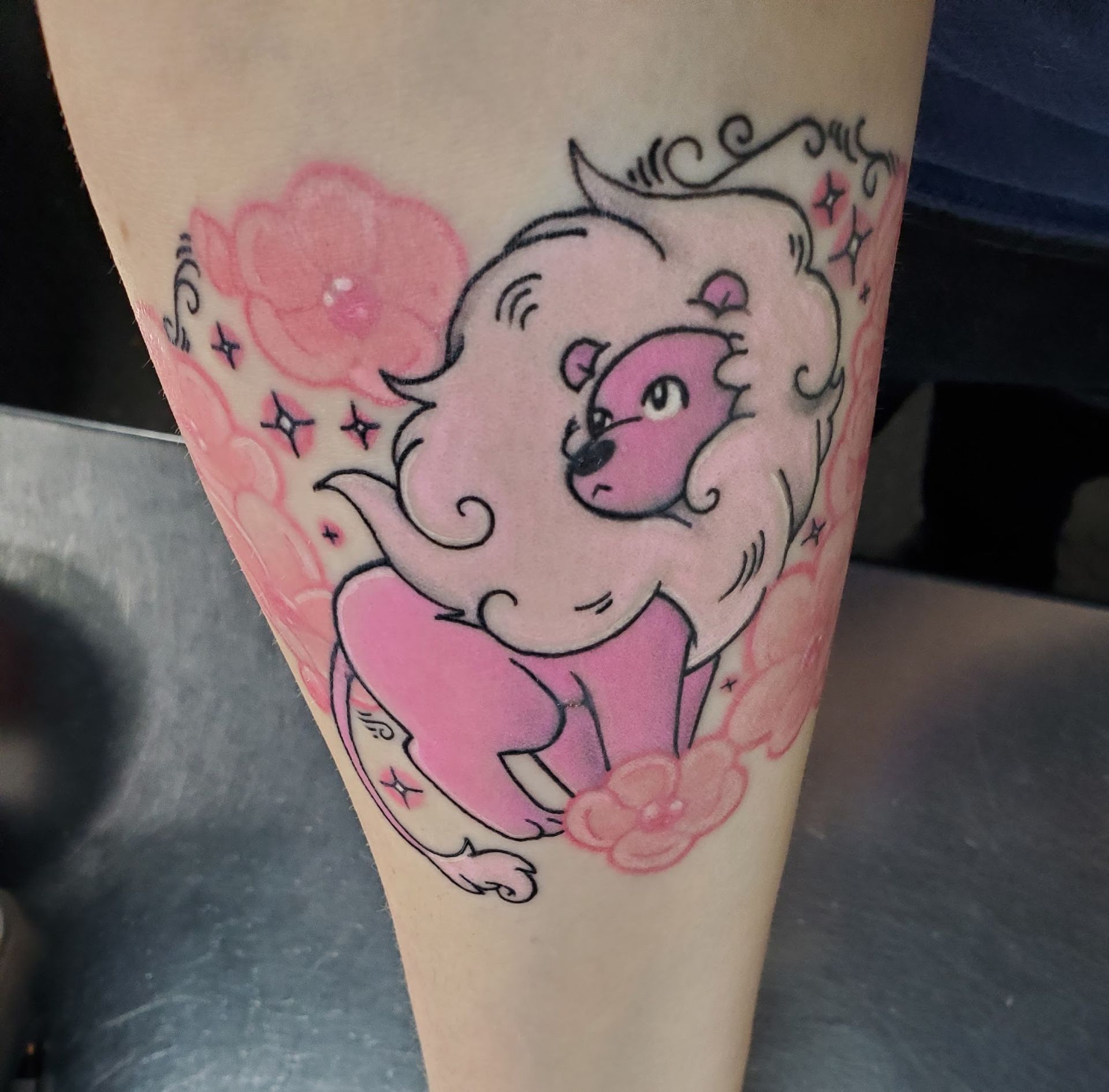 A person has a pink lion tattoo on their leg