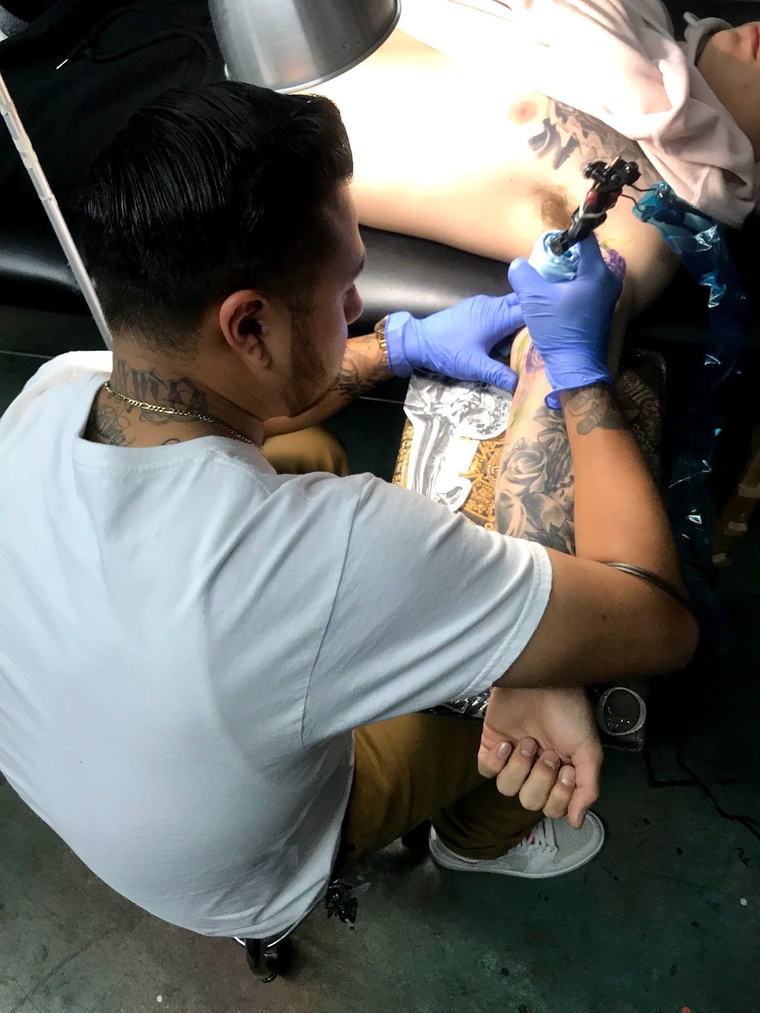 A man is getting a tattoo on another man 's arm.