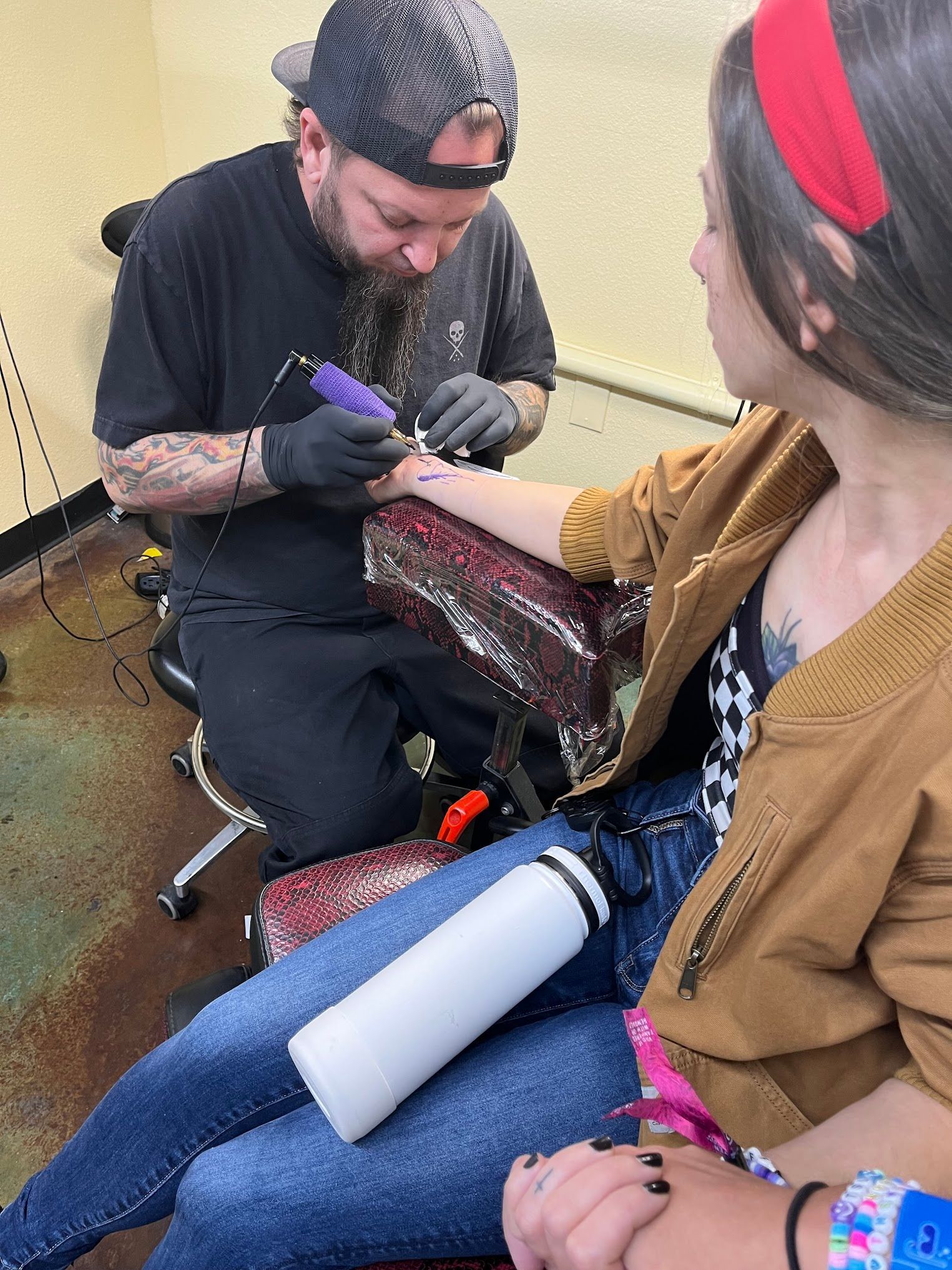 A man is getting a tattoo on a woman 's arm.
