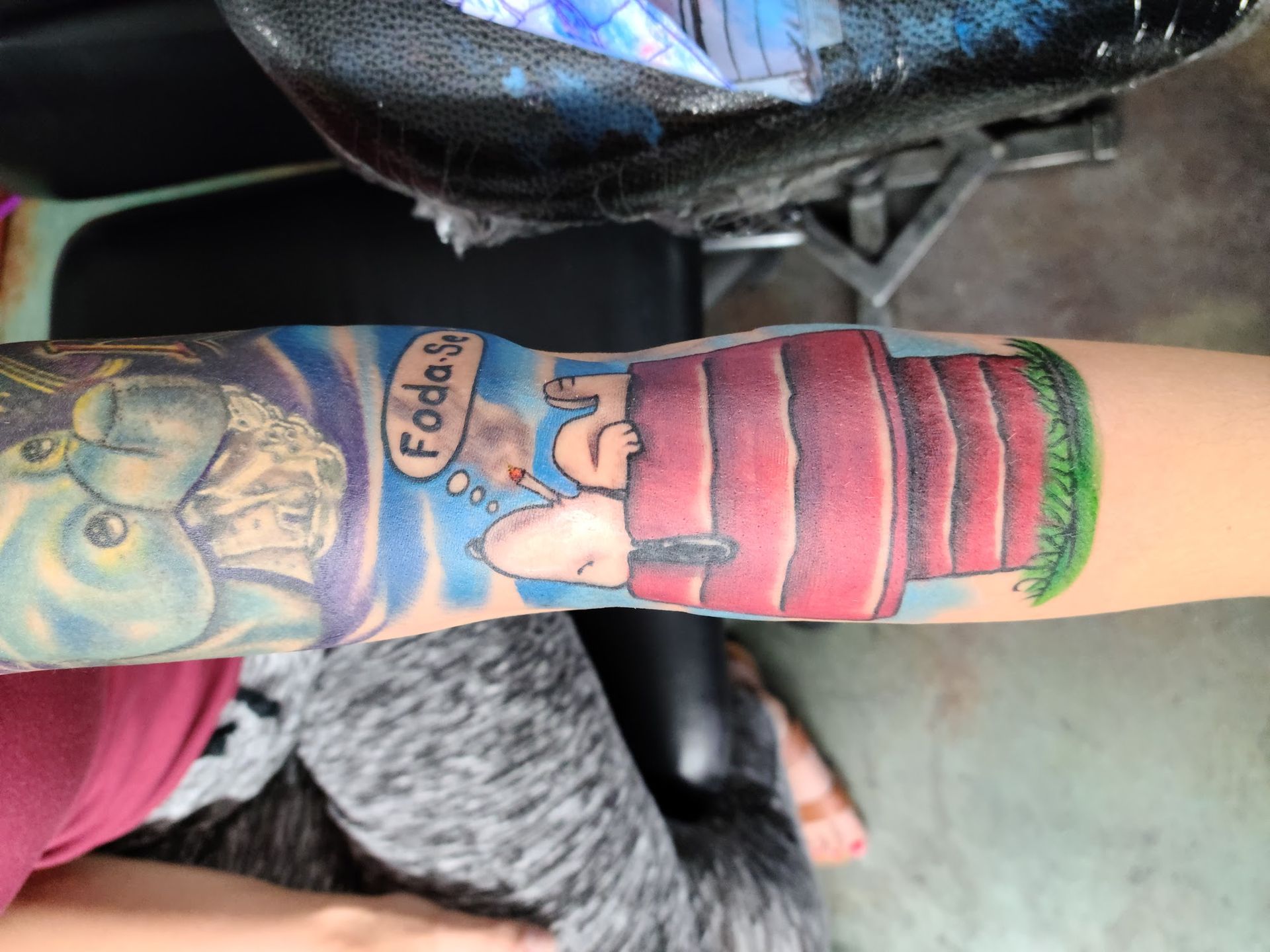 A person has a tattoo of snoopy on their arm