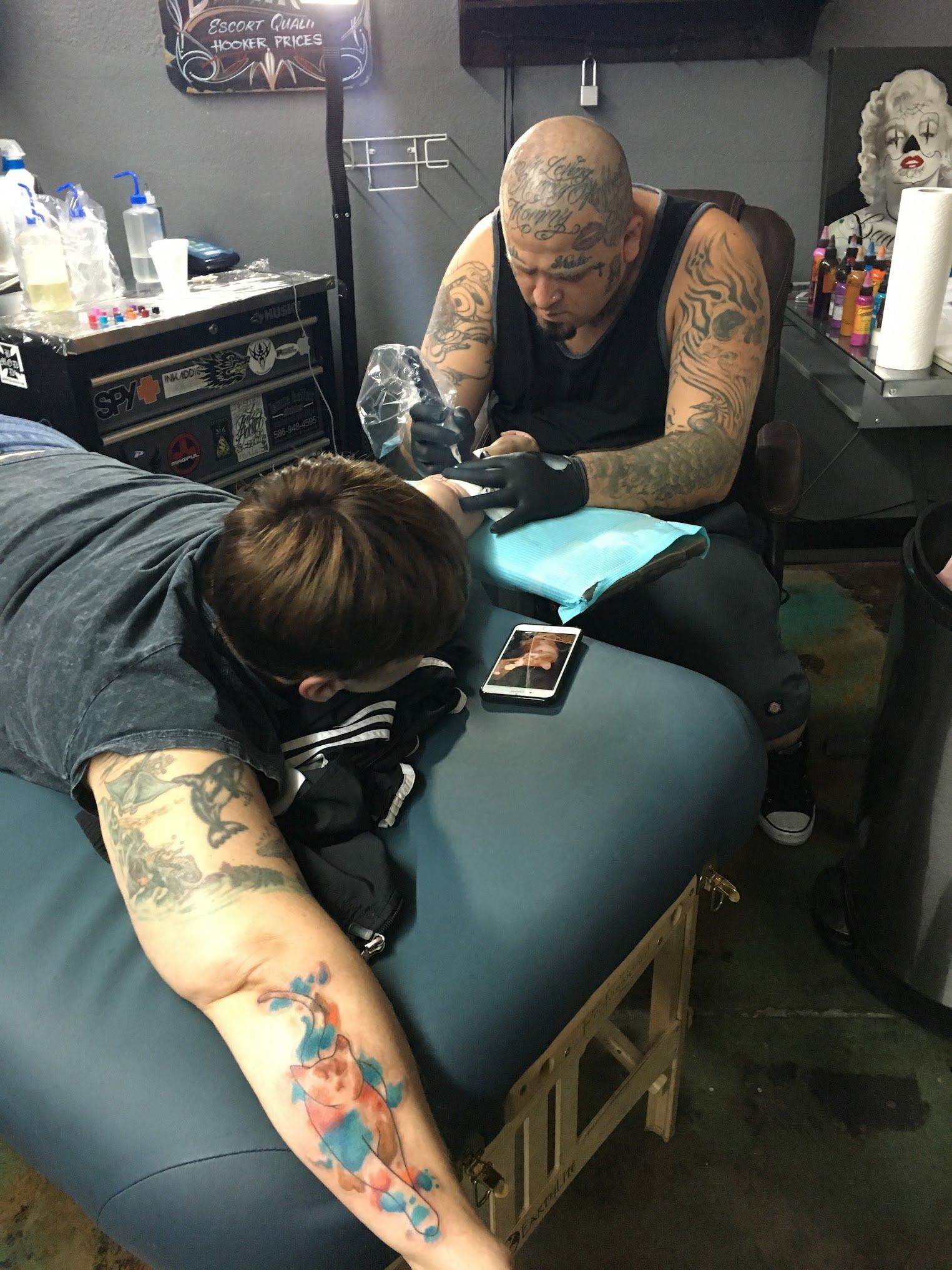 A man is getting a tattoo on another man 's arm.