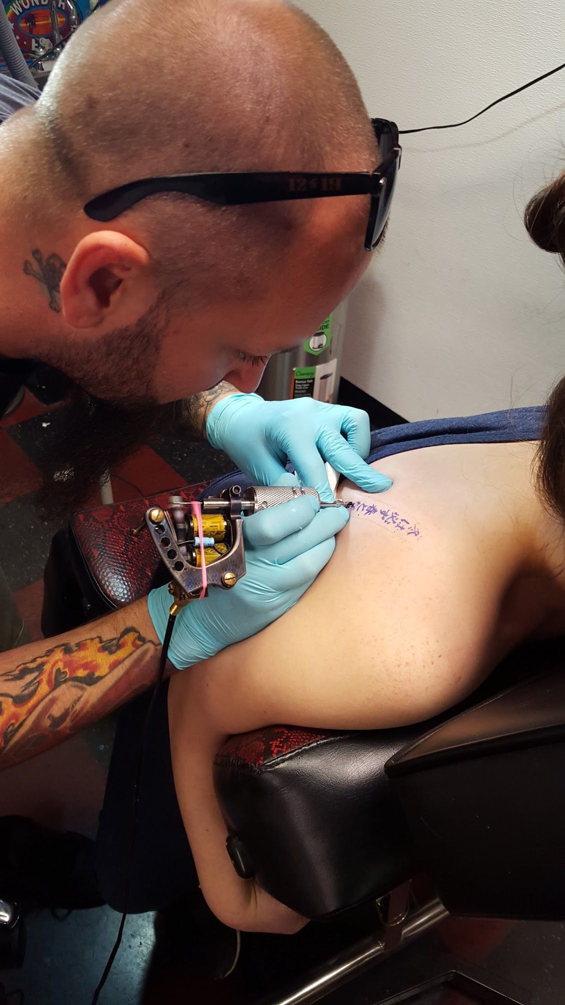 A man is getting a tattoo on a woman 's back.