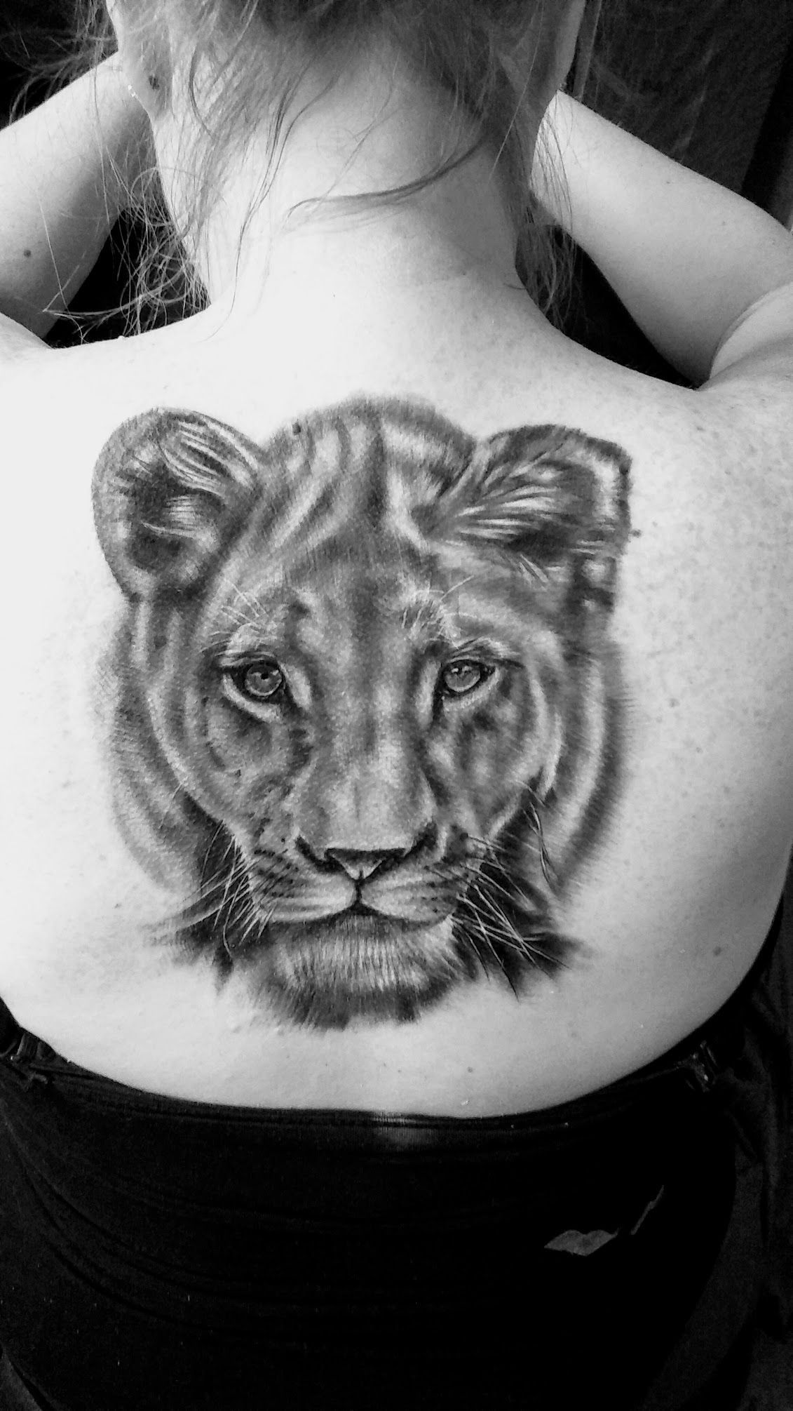A woman has a tattoo of a lioness on her back.