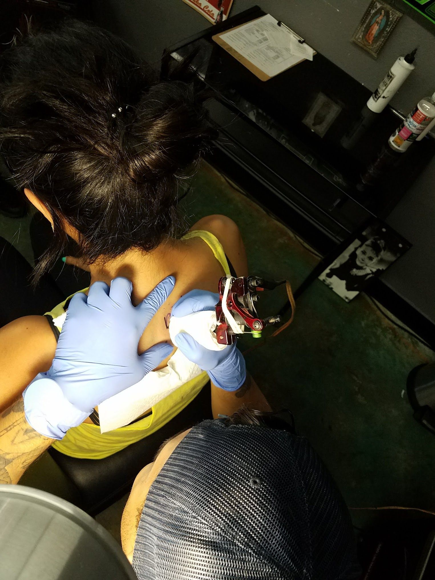 A woman is getting a tattoo on her back by a tattoo artist.