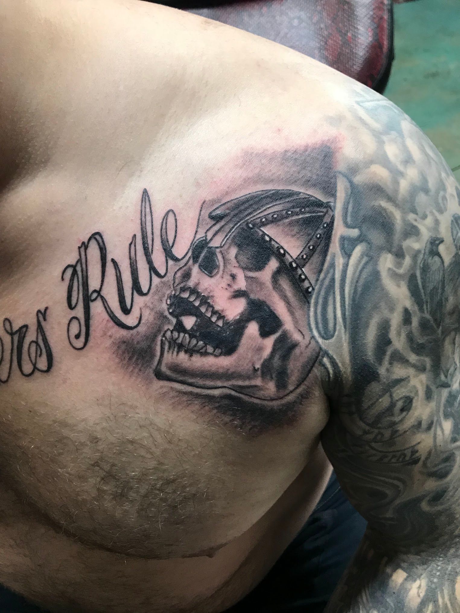 A man has a tattoo of a skull and the word rule on his chest.
