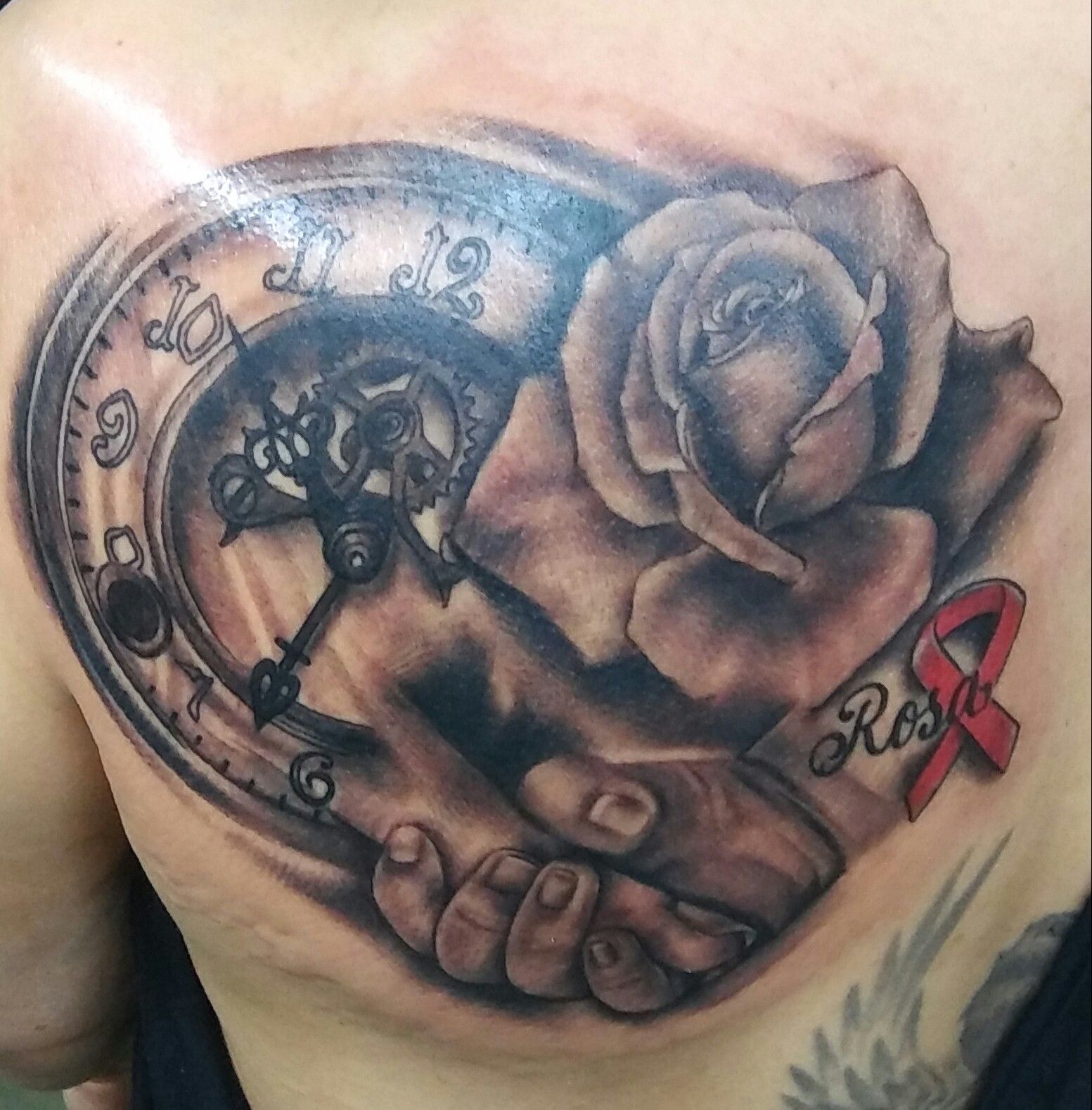 A man has a tattoo of a rose and a clock on his back