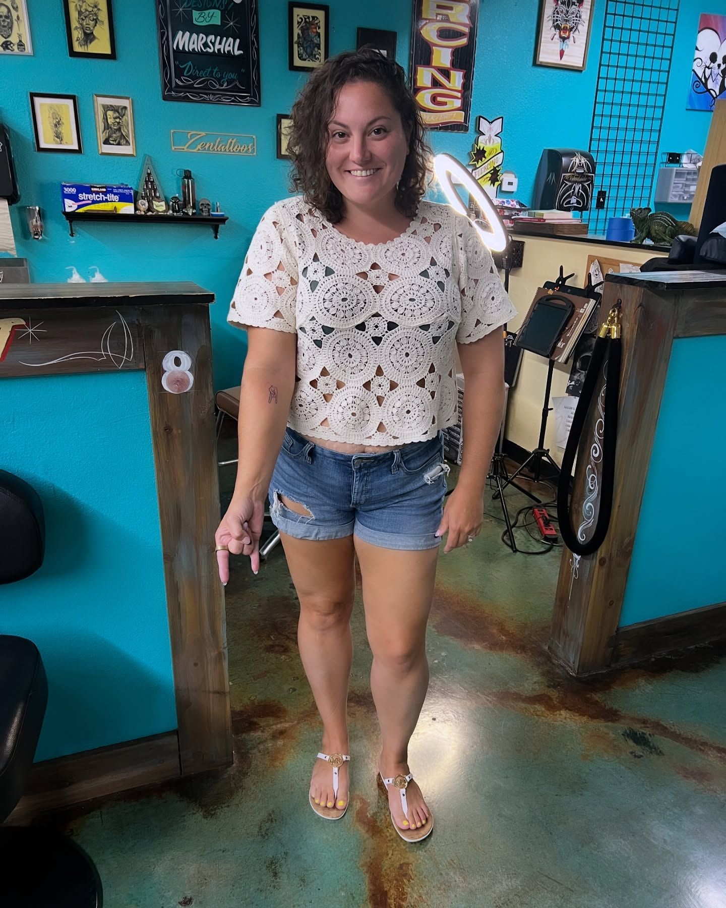 A woman wearing shorts and a crop top is standing in a room.
