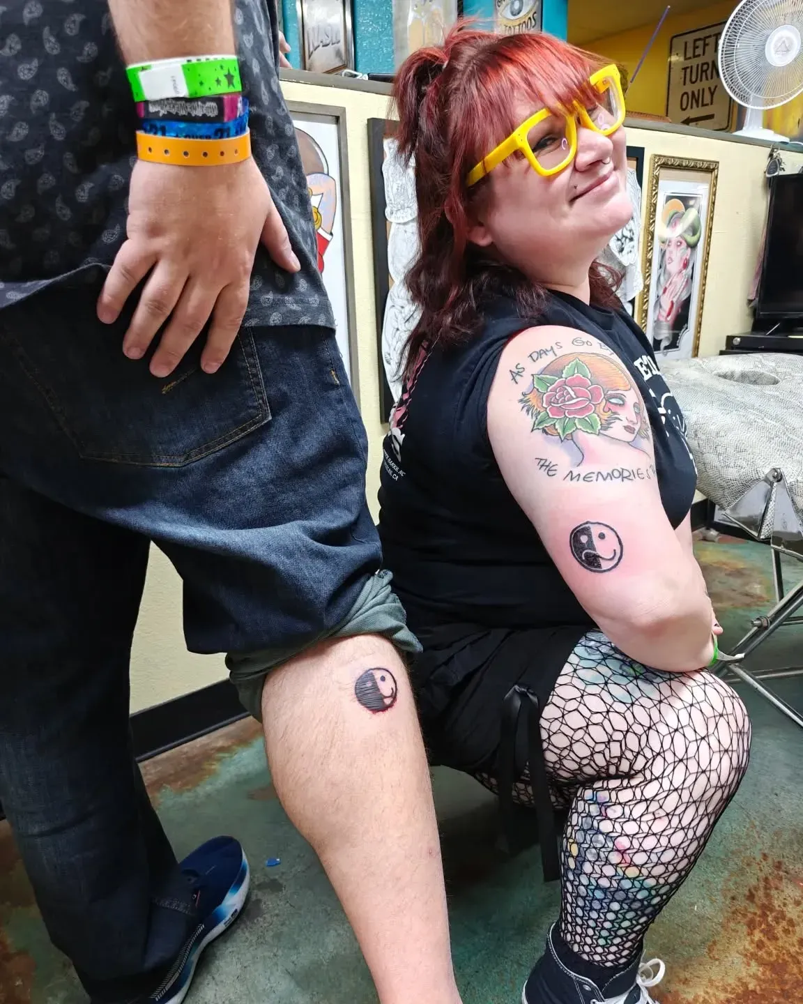 A woman is kneeling next to a man with a tattoo on her leg