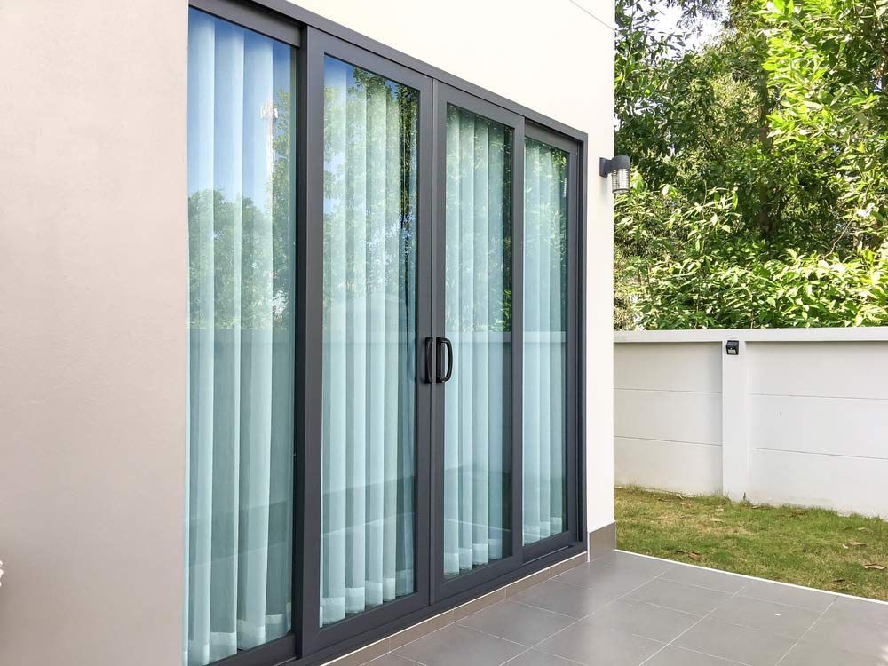 A Patio With Sliding Glass Doors And Curtains — Smith Aluminium In Hamilton, NSW