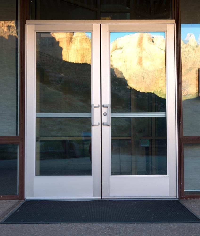 A Pair Of Glass Doors With A Black Mat In Front Of Them — Smith Aluminium In New Lambton, NSW