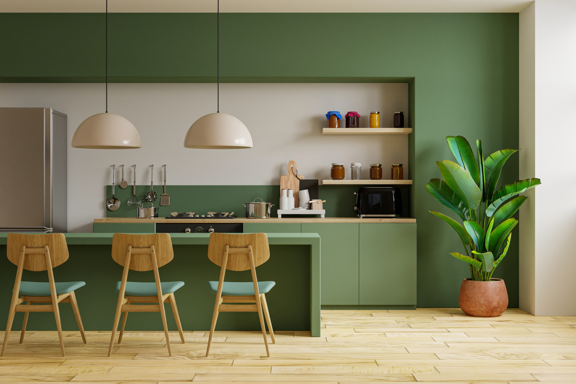 A kitchen with green cabinets , wooden floors , stainless steel appliances and a plant.