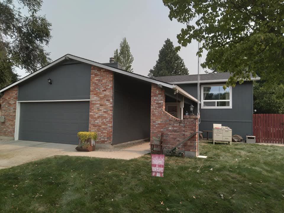 Exterior paint job of a house with a gray siding and a red brick wall