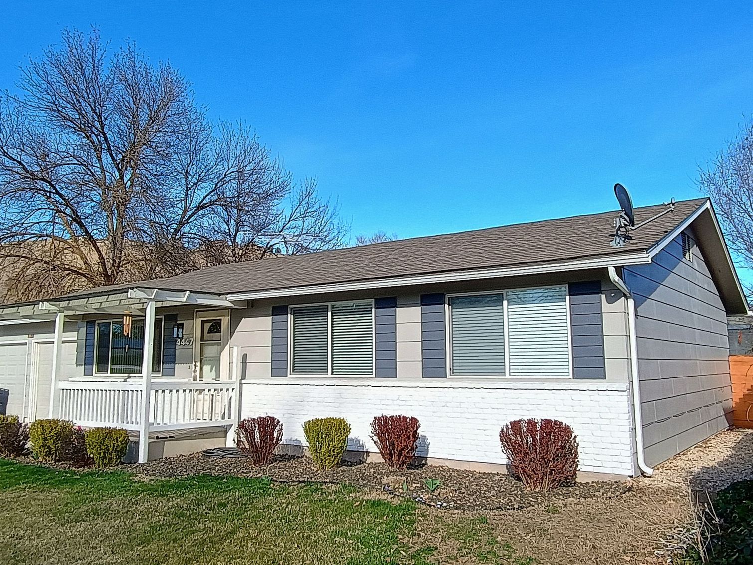 A small house with a porch and a satellite dish on the roof.