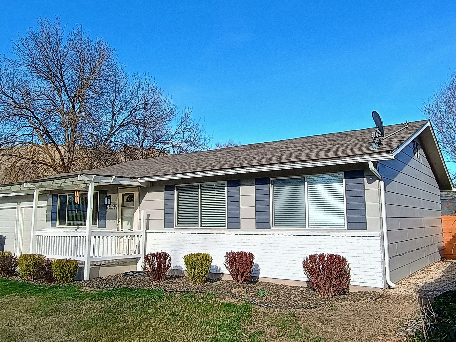 Exterior paint job of a small house with a porch and a satellite dish on the roof. Exterior painting in Boise, ID.