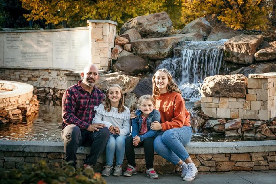A family is posing for a picture in front of a waterfall.