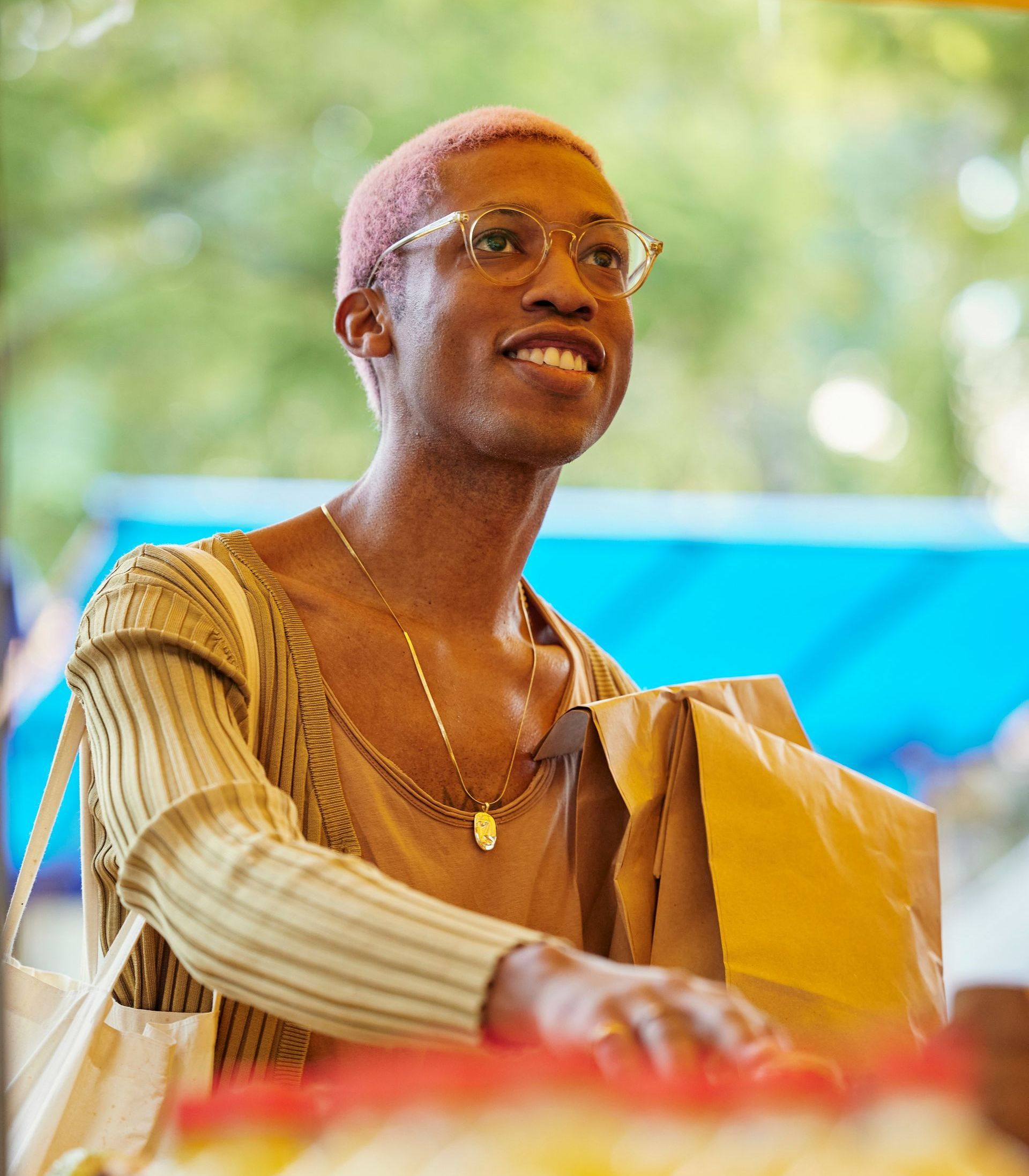 A woman wearing glasses and a necklace is smiling