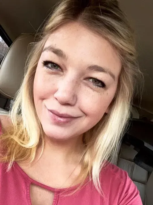 A woman is taking a selfie in the back seat of a car.