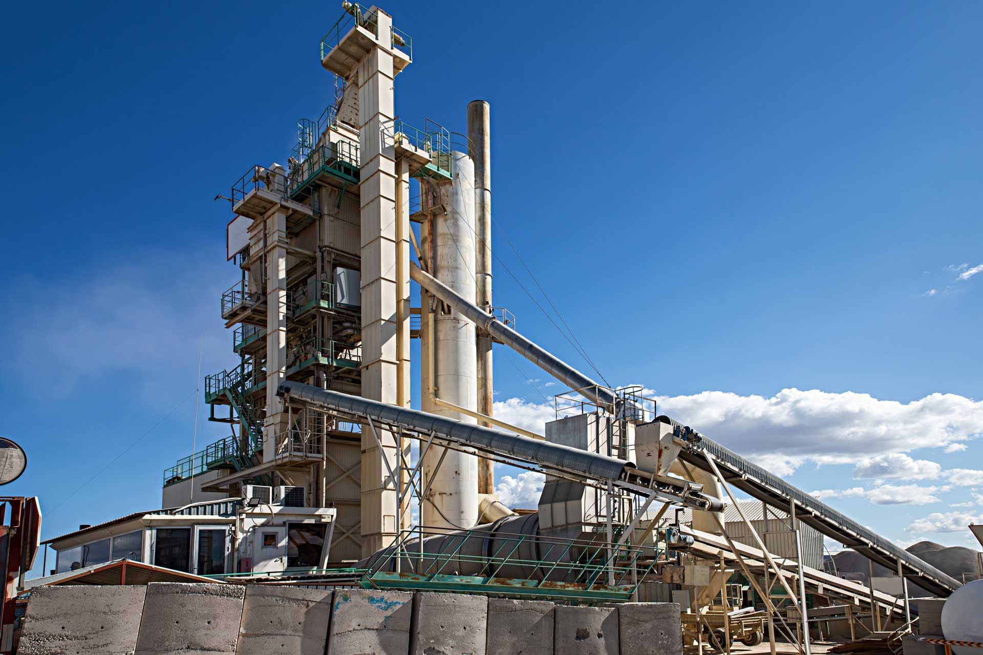 Industrial cement plant against a bright blue sky.