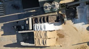 Aerial view of a construction material yard, showing piles of sand, gravel, and concrete blocks.
