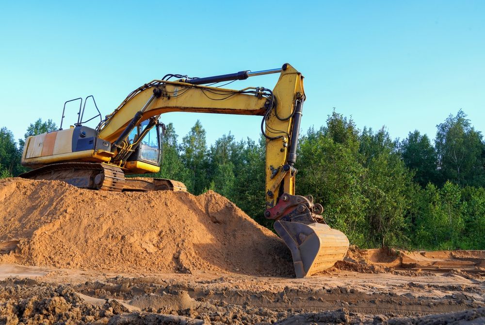 A Yellow Excavator Parked on a Large Pile of Sand — GPE Plumbers In Kendall, NSW