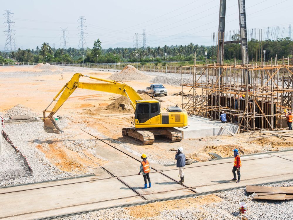 Construction Site with Yellow Excavator, Workers in Hard Hats — GPE Plumbers In Kendall, NSW