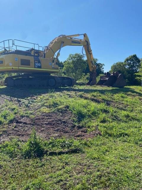 A Yellow Excavator Rests on Sandy Ground at a Construction Site — GPE Plumbers In Kendall, NSW