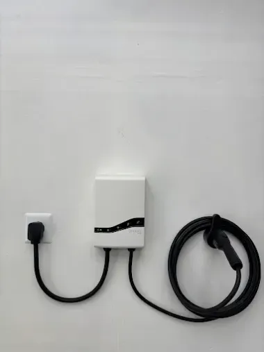 Wall-mounted white charging box with a black cable and coiled cord on a light wall.