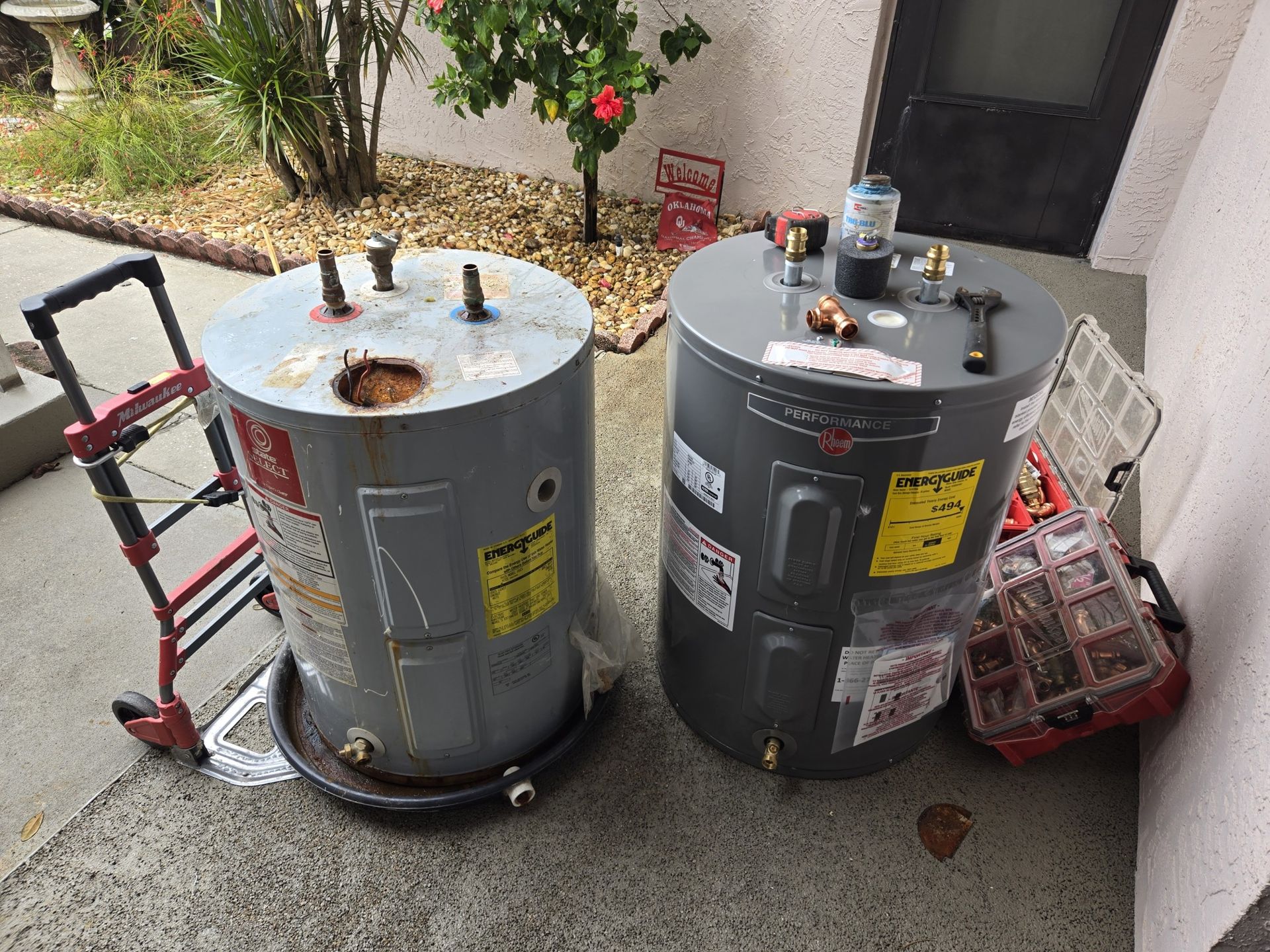 Two water heaters are sitting next to each other on a sidewalk.