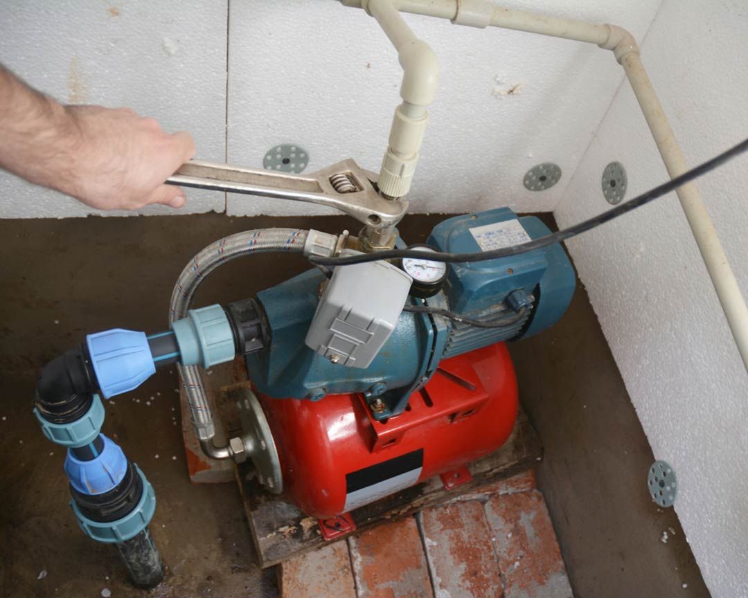 A person is working on a water pump with a wrench