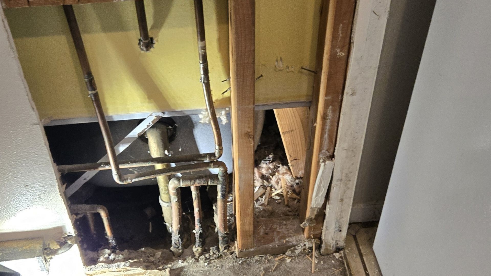 A room with a hole in the wall and pipes coming out of it.