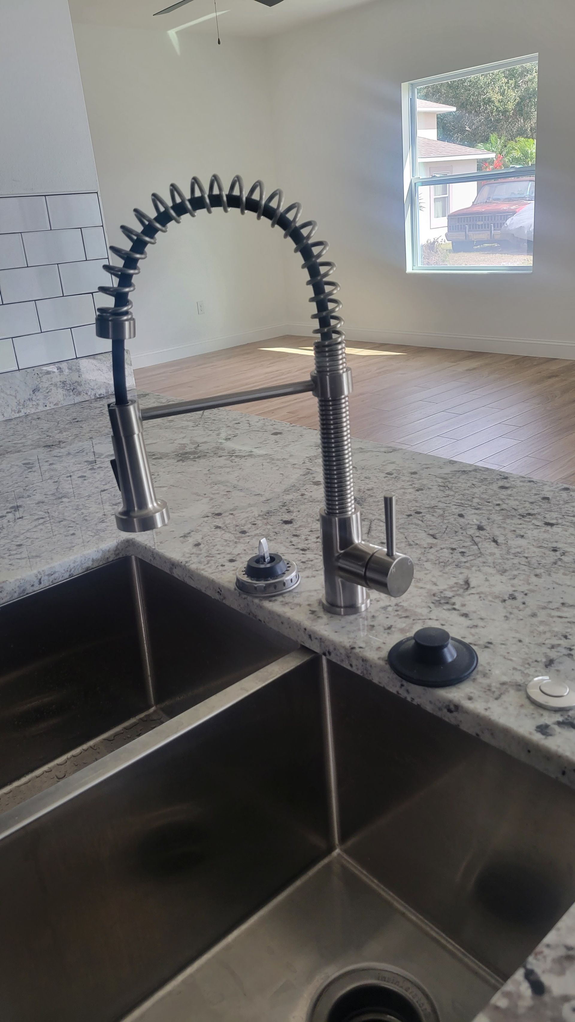 A kitchen sink with a stainless steel faucet on a granite counter top.