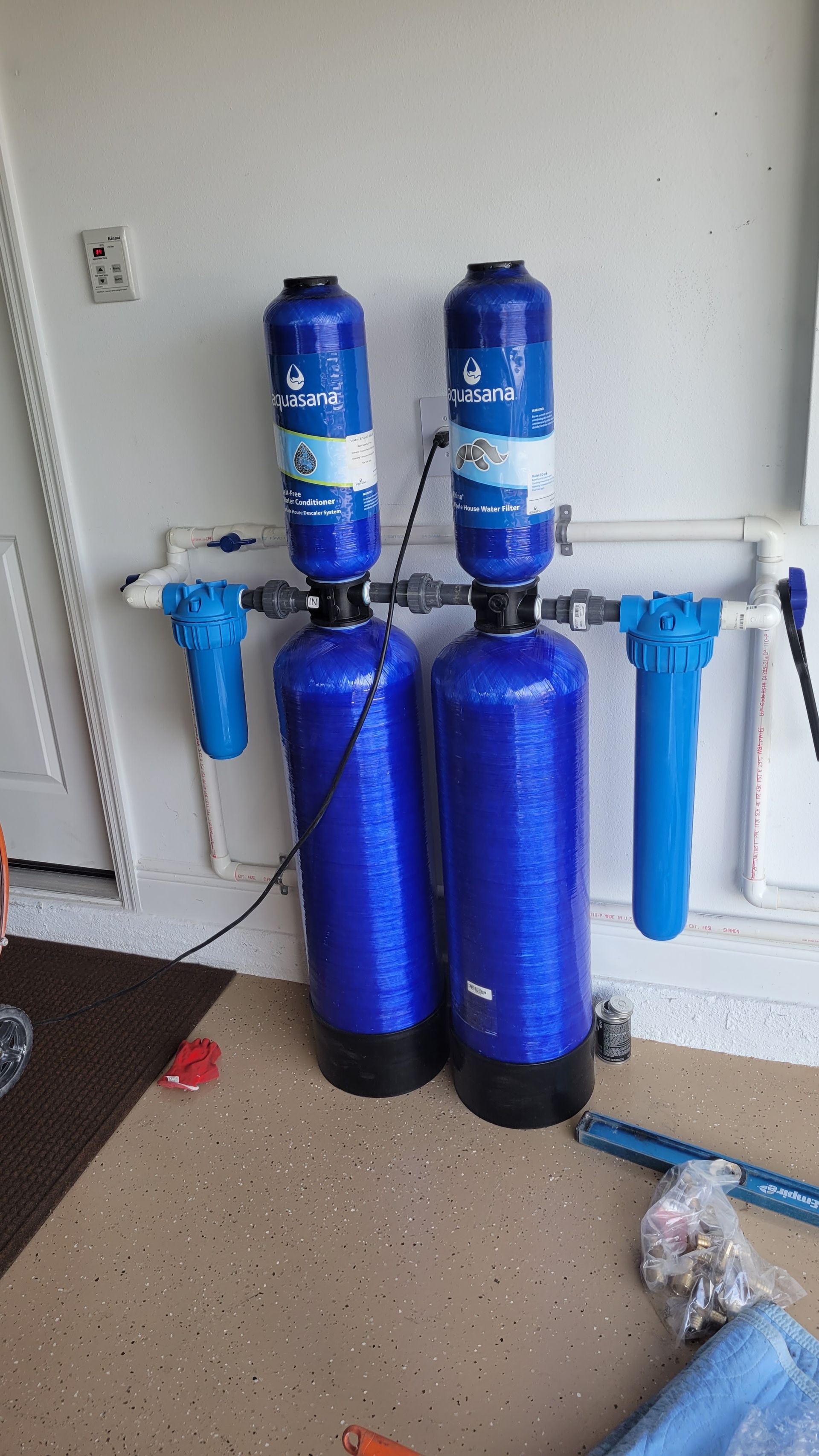 Two blue water filters are sitting on the floor in a garage.