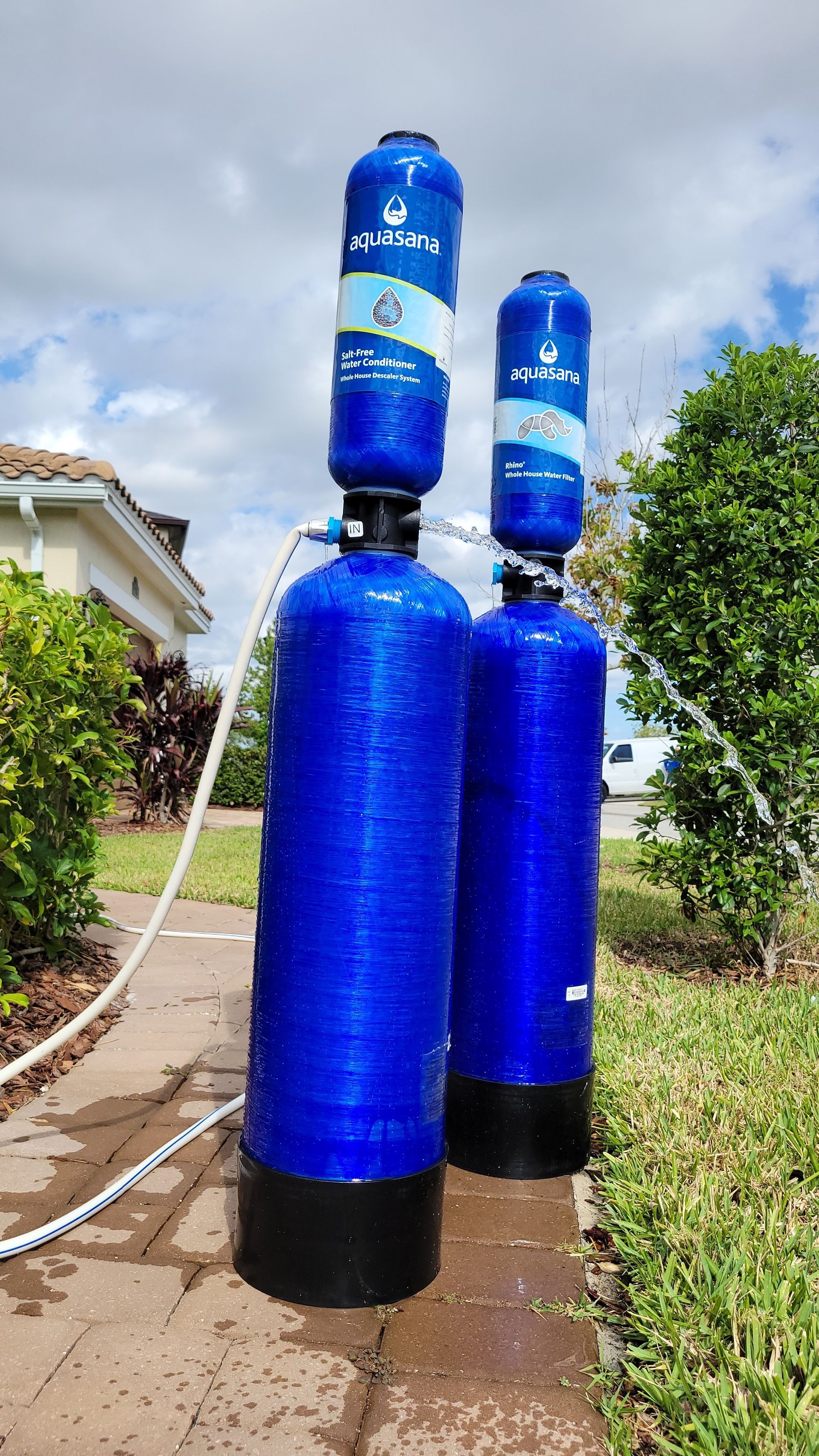 Two blue water tanks are sitting next to each other on a sidewalk.
