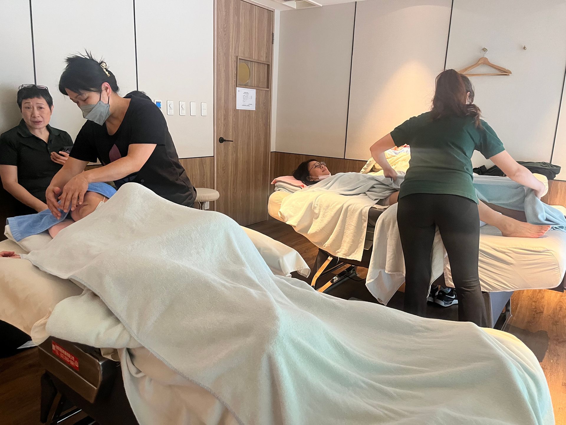 水療中心員工正在進行臉部護理並準備按摩床。