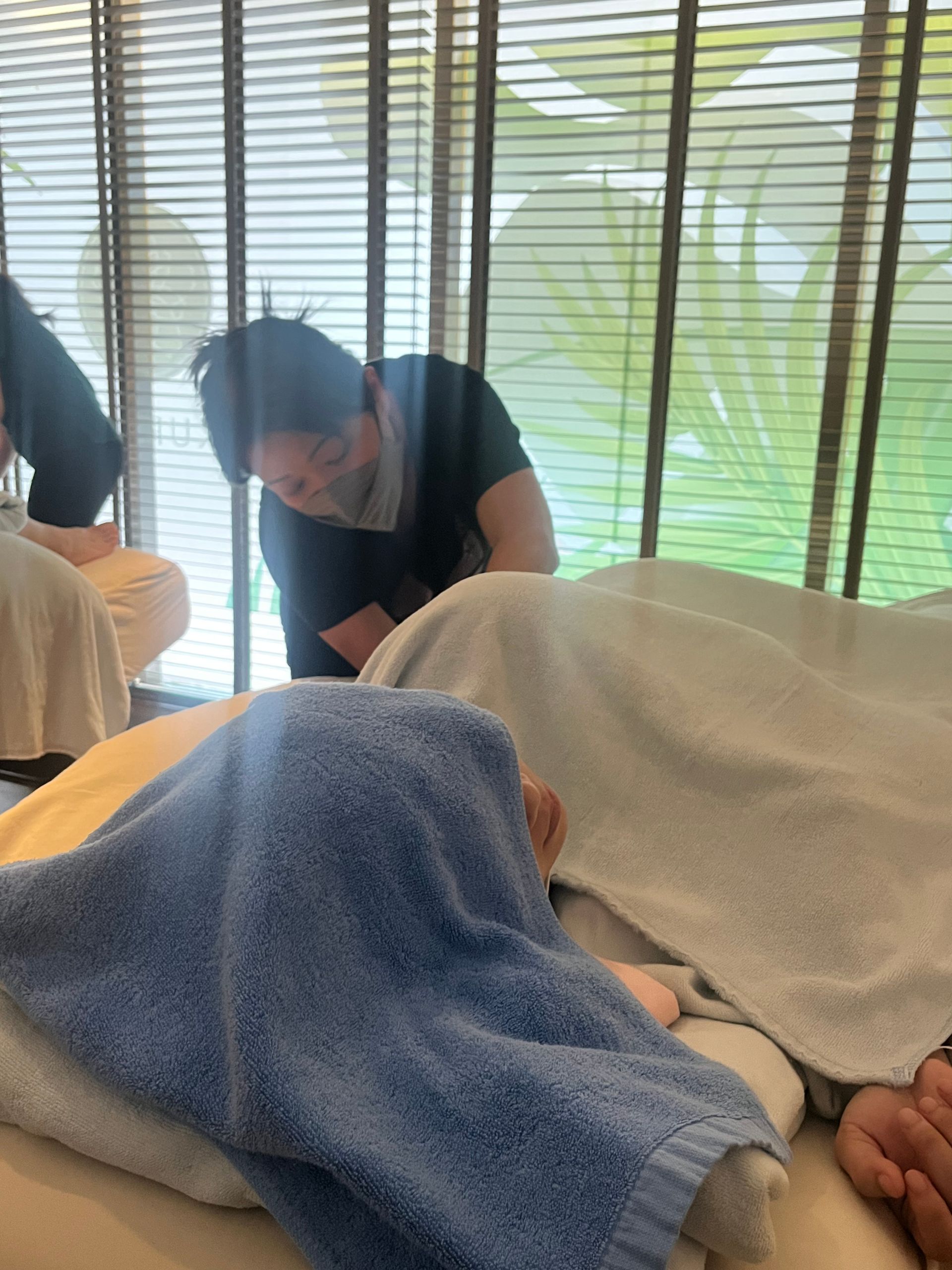 在類似水療中心的房間裡,有人正在為躺著、蓋毛巾的人做足部按摩。