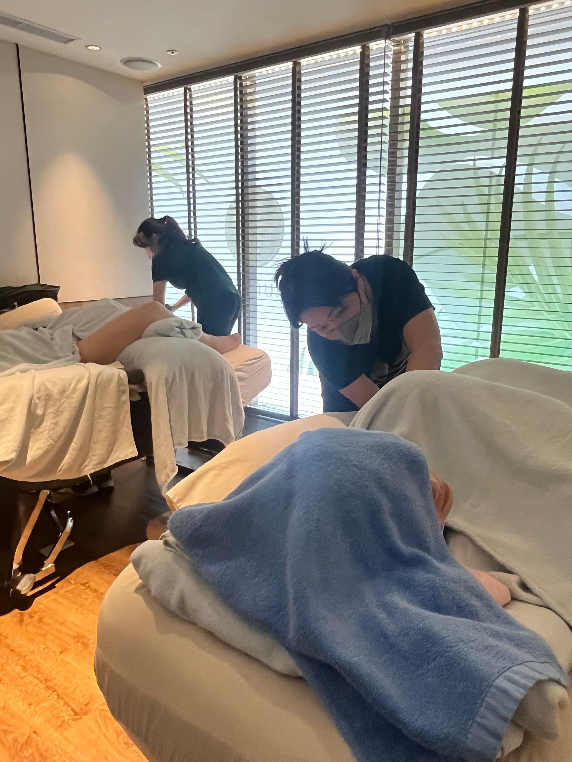 兩名顧客在水療中心接受按摩，物理治療師正在為他們服務。