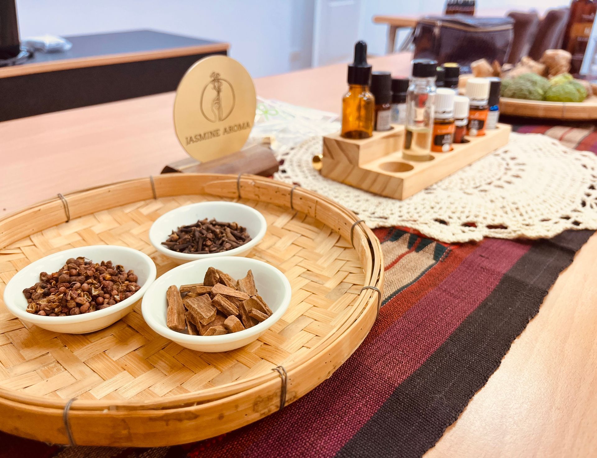 芳香療法工作坊：碗裡盛放著各種原料，桌上放著精油瓶和木製logo，旁邊還有一個編織托盤。