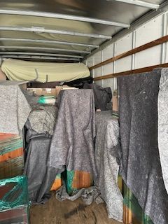 Truck cargo area packed with hanging gray and black blankets and covered items
