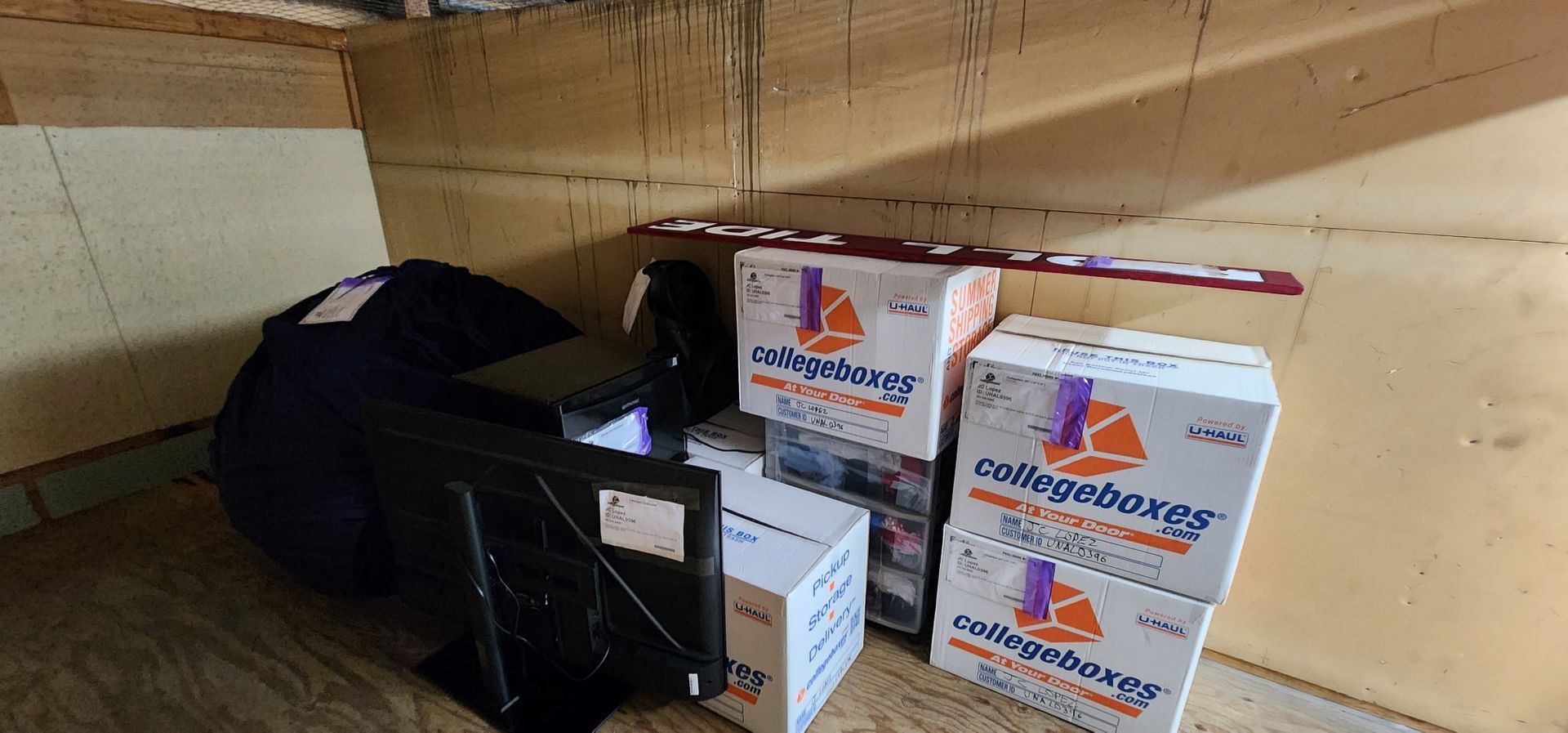 Boxes and a black bag stacked in a cardboard-lined storage area
