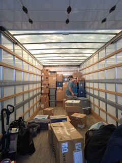 Moving truck interior packed with cardboard boxes and bags during a move.