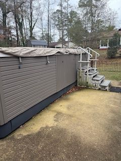 Above-ground pool with a tarp cover, white steps, and a yellowed backyard lawn