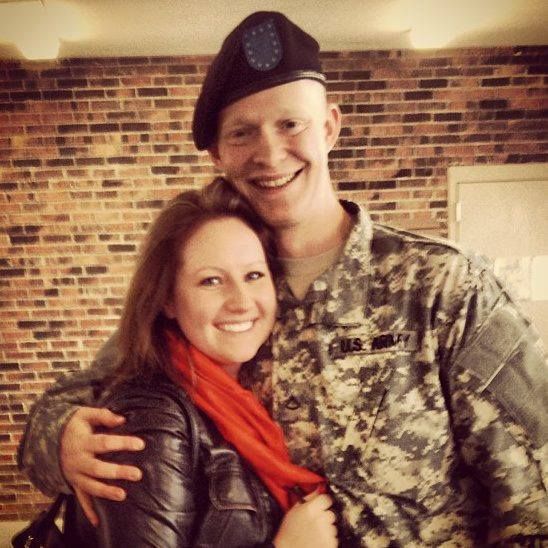 Family posing with a gorilla statue. A child holds a lollipop. Green trees in background.