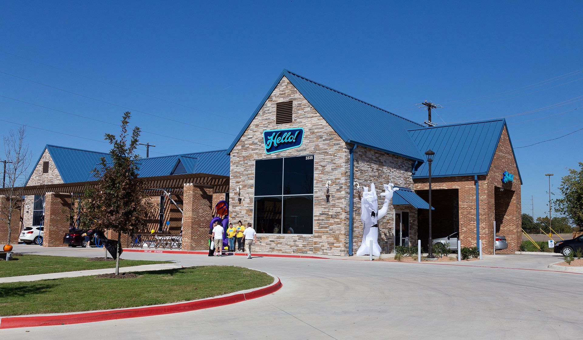 Stone building with blue roof, large window, and signage; exterior view under clear sky.