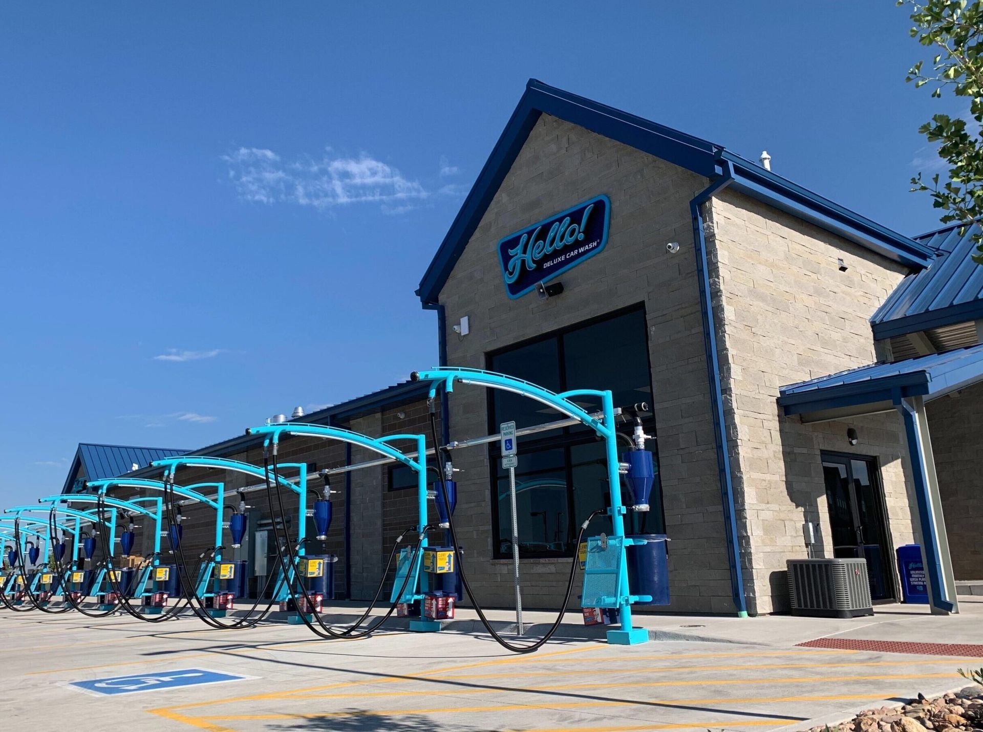 Exterior of a teal and blue car wash building under a clear sky.