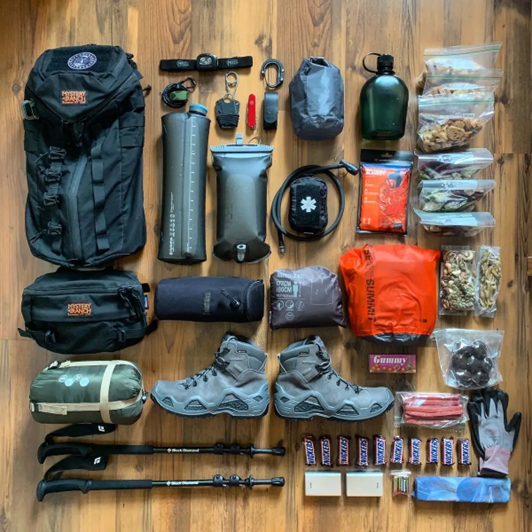 A flat lay photo showing a full set of organized hiking gear, including a backpack, boots, trekking.