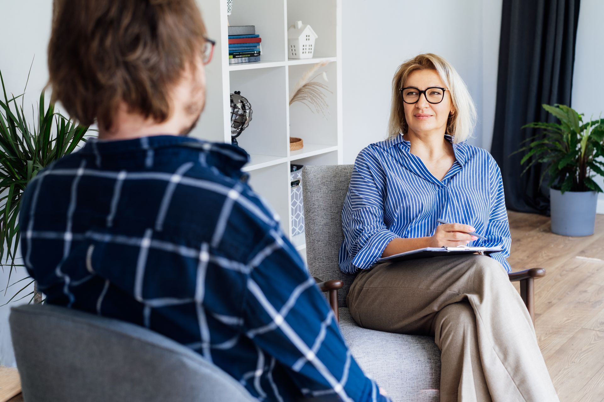 A woman is sitting in a chair talking to a man.