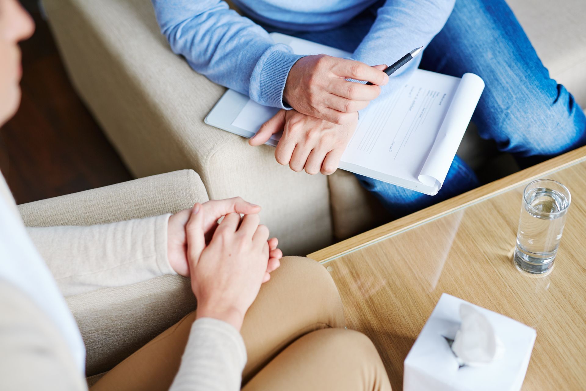 A woman is holding a man 's hand while sitting on a couch.